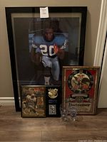 Full view of the lot showing framed football photo, Beckett plaque, Budweiser clock and Coca-Cola glasses arranged on floor