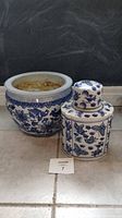 Photo showing both the blue and white Bombay ceramic tea jar and the porcelain planter together on tiled floor against black background.