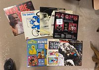 Vinyl records on floor showing covers of The Rolling Stones, The Smurfs, Village People, Sesame Street, and Holiday Magic Christmas theme.