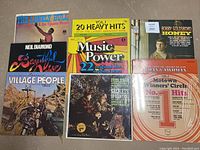 Top view of 9 vinyl record album covers showing various artists and compilations including Neil Diamond, Village People, Bobby Goldsboro, and more.