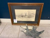 Framed detailed line art print of homestead scene with trees by R.P. Rudkin, matted and wood framed, alongside five silver bird mirror decorative pieces on floor.