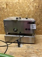 Full front view of the stainless steel water distiller on wooden surface