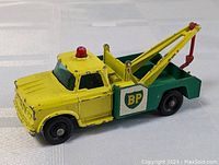 Front-side view showing the yellow and green BP tow truck with some paint wear and detailed towing equipment.