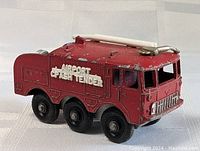 Front and near side view of the red diecast fire truck labeled Airport Crash Tender showing paint wear and part of the white hose reel on top