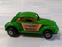 Side profile of the green die cast Volkswagen Beetle with Dragon Wheels decal and black wheels.