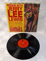 Front view of the vinyl record and album cover, showing the cover's colorful illustration and red center label on the vinyl disc.