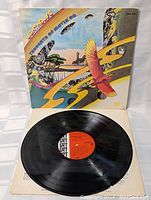 Vinyl record disc with orange R T label and black text, placed on a paper sleeve.