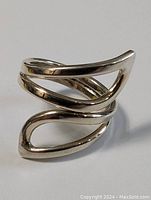 Close-up photo of the ring showing the abstract swirl open band design from a slight angle.