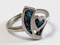 Close-up front angle of the sterling silver ring showing turquoise inlay and heart cut-out design.