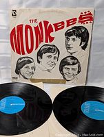 Both vinyl LP records shown with cover that has red The Monkees logo and black-and-white band member portraits. Vinyls look clean and appear free of scratches.