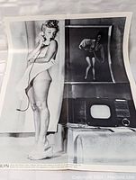 Full view of black and white Marilyn Monroe image standing on phone with TV and reflection behind her, part of the poster.