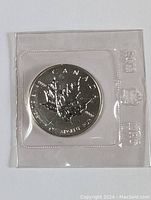 Top view of the sealed silver coin showing full maple leaf design and inscriptions.