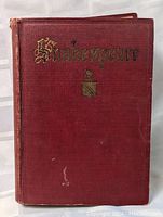 Front cover of large antique fireside edition of Shakespeare's Complete Works. Red cloth cover with gold embossed title and emblem. Shows signs of wear including scuff marks and edge wear.