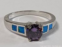 Close-up front view of the sterling silver ring with amethyst center and blue opal inlay on band.