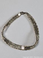 Full view of vintage sterling silver thick bracelet laid out in a triangular shape, showing the entire length and lobster clasp.