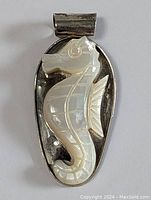 Front view of the sterling silver pendant with carved mother of pearl seahorse showing details of the carving and silver backing.
