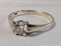 Front and angled views of the sterling silver ring showing the clear round crystal and polished band.