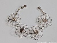Front view of sterling silver daisy chain bracelet showing four daisy flower links and adjustable clasp.