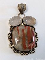 Front view of sterling silver pendant with three stones, silver decorative border and bail detailing