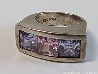 Close-up front angle of the sterling silver ring showing three square stones with pink center and lavender sides, marked 925 inside band.