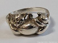 Close up image of the ring showing the full cat figure with detailed features and textured fur, highlighting the patina and condition.