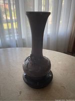 Front view showing dragon motif and overall shape of vase with black wooden stand.