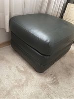 Angled side view showing leather upholstery, stitching, and overall shape of the stool.