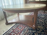 Side view showing wooden base with triangular support and square legs on a patterned rug.