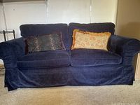 Front view of navy blue fabric 2 seat couch with two decorative pillows on it, showing size and condition.