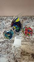 Three art glass fish sculptures arranged side by side on marble countertop.