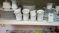 Full arrangement of Crown Ming china on shelf showing plates, cups, and saucers.