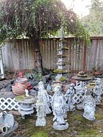 Multiple garden statues, lanterns, pagodas and planters grouped on ground