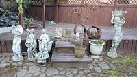 Overall group shot of 12 garden statuary pieces including human-figure statues, metal sculptures and planters