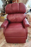 Front view of maroon leather power lift and recline chair with remote resting on right arm.