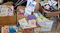 Three large cardboard boxes filled with dozens of assorted greeting cards and envelopes for multiple occasions like birthdays and holidays.