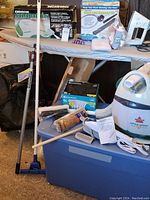 Overall lot including ironing board, cleaners, accessories, storage bin and travel bag