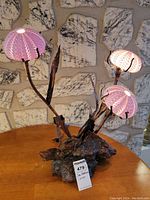Lamp viewed front on, lit to show pinkish glow of the three sea urchin shell shades.