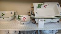 Full view of two bowls and two rectangular casseroles with wire racks on shelf showing botanical designs.
