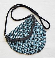 Front view of blue, white and black enamel mesh purse with scalloped flap and black braided rope strap.