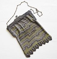 Full view of the enamel mesh purse showing its rectangular shape, geometric pattern in gold, yellow, black and white tones, metal frame with chain handle laid flat.