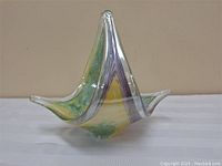 Front angled view showing the pointed tip and curved colorful sides of the glass sculpture.