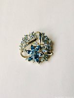 Front view of blue rhinestone brooch showing mixed sky blue and pale blue stones in silver tone setting.