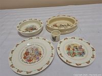 Overview of five Bunnykins-themed ceramic dinnerware items including plates, bowls, and a small cup.