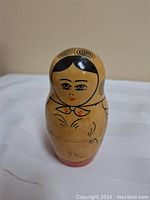 Front view of the largest nesting doll showing facial and head scarf details