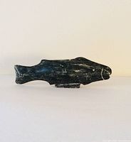 Side view of dark soapstone fish carving showing shape and carved details