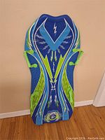 Front view of blue plastic toboggan sled with neon green and white lightning bolt graphics, shows handles and overall shape and design.