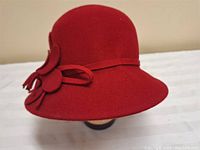 Side view showing the flower and tassel detail on the red wool cloche hat.