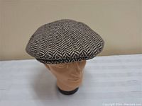 Brown and cream herringbone tweed flat cap shown from front angle on mannequin head.