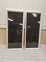 Front view of two large white rectangular frames side by side against a wall.