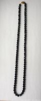 Full length image of the black jet facetted bead necklace showing string of uniformly sized round beads and clasp.